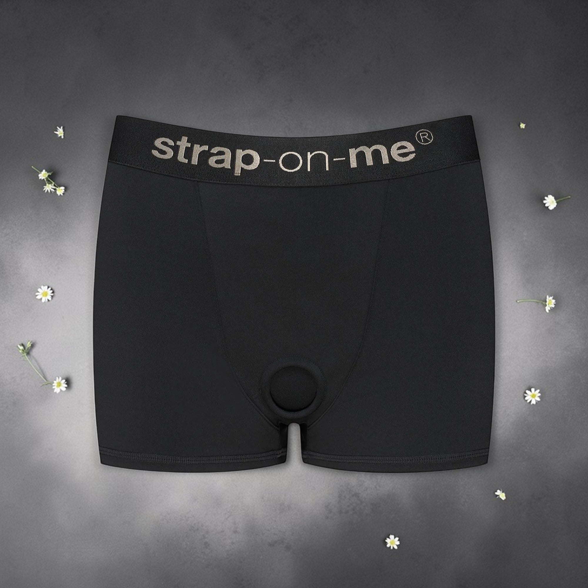 Black strap-onme product on a gray background with small flowers.